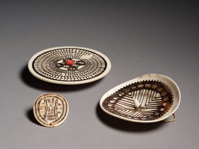 trois pièces de poterie ornées de motifs, posées sur une table
