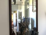 un miroir accroché au mur au-dessus d'une table sur laquelle sont posés des vases