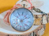a silver pocket watch on a piece of wood on a yellow background