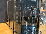 a coffee maker sitting on a wooden table next to a box of krups