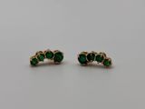 a pair of emerald earrings on a white surface
