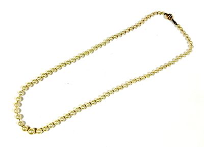 a close up of a gold chain with beads on a white background