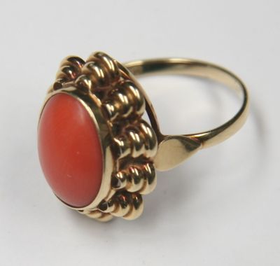 a close up of a gold ring with a red stone