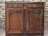 une vieille armoire en bois adossée à un mur de pierre, devant un mur de briques