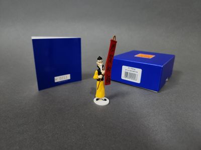 une petite figurine représentant un homme tenant un crayon devant une boîte bleue