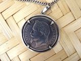 a silver coin with a face on it on a chain