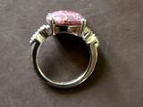 une bague sertie d'une pierre rose, posée sur une table