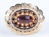 une image représentant une bague en or sertie d'une pierre de grenat entourée de grenats