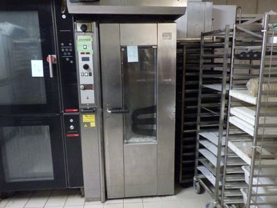 un four professionnel dans une cuisine professionnelle, à côté d'un support à plateaux