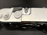 a silver camera with a black strap on a black surface