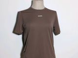 Le t-shirt est marron et porte un logo blanc.
