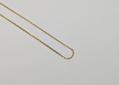 a gold chain necklace with a single diamond on a white background