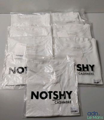 quatre sacs de t-shirts blancs posés sur une table