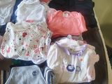 a pile of baby clothes on a bed in a room