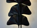 a large metal sculpture of a leaf on a stand