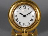 a small gold clock with roman numerals on it