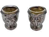 two silver vases sitting next to each other on a white surface