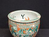 an orange and green bowl with a bird on it sitting on a black surface