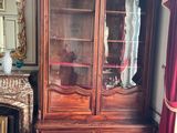 a wooden cabinet with a glass door in the corner of a room