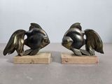 une paire de sculptures de poissons en bronze posées sur des socles en marbre, disposées sur une table
