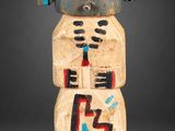 un gros plan sur une statue en bois représentant un robot, posée sur une surface grise
