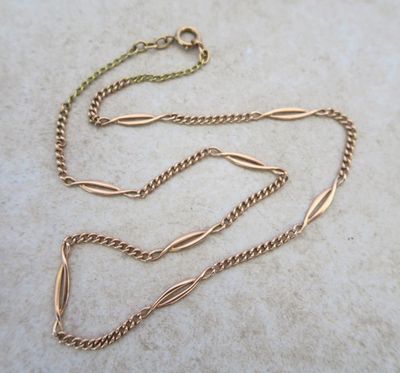 a close up of a gold chain on a marble surface