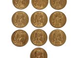 six gold sovereigns of various sizes and shapes on a white surface