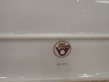 a close up of a white dish with a brown logo
