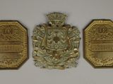 trois médailles d'or représentant des armoiries sur fond blanc