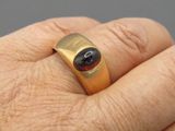 la main d'un homme tenant une bague sertie d'une pierre noire