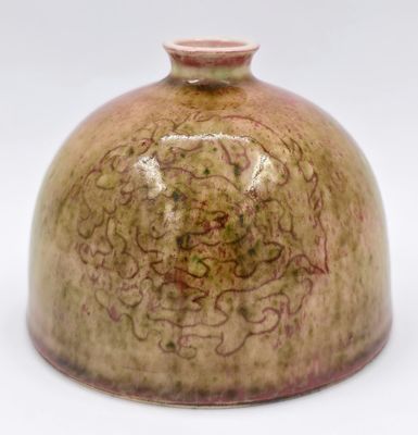 un vase brun posé sur une surface blanche