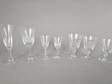 six verres à vin vides alignés en rang sur une surface grise