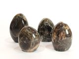 quatre œufs en marbre noir posés sur une surface blanche