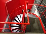 a red spiral staircase going up to the top of a building