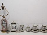 a table with a vase, cups, and a lamp on it