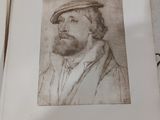 un dessin représentant un homme coiffé d'un chapeau, assis sur un livre