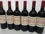 six bottles of red wine are lined up on a table