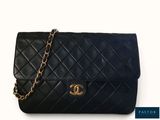un sac Chanel noir auquel est suspendue une chaîne dorée