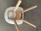 a white chair with wooden legs on a carpeted floor
