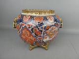 un grand vase à bord doré posé sur un socle