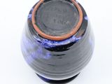 a black and blue vase with a brown rim on a white surface