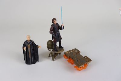 Des figurines « Star Wars » sont posées sur une surface blanche, à côté d'une petite voiture