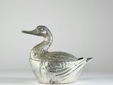une image représentant un canard en métal posé sur une surface blanche
