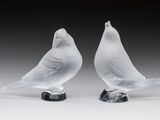 une paire d'oiseaux en verre blanc posés sur un socle noir