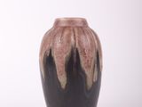 un vase noir et marron posé sur une surface blanche