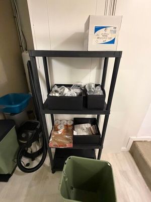 une étagère noire sur laquelle sont posés plusieurs bacs contenant de la nourriture