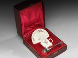 une petite tasse et une soucoupe dans une boîte rouge