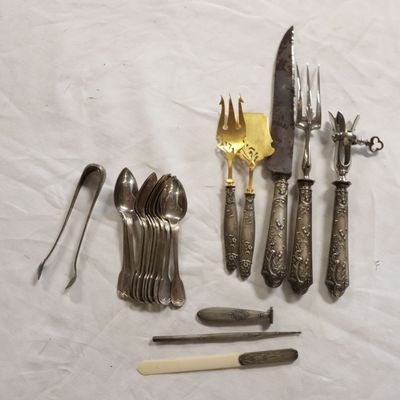 many different types of silverware on a white table