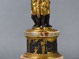a statue of a man holding a lamp on a pedestal