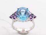 a close up of a ring with a blue topaz and purple amethtites